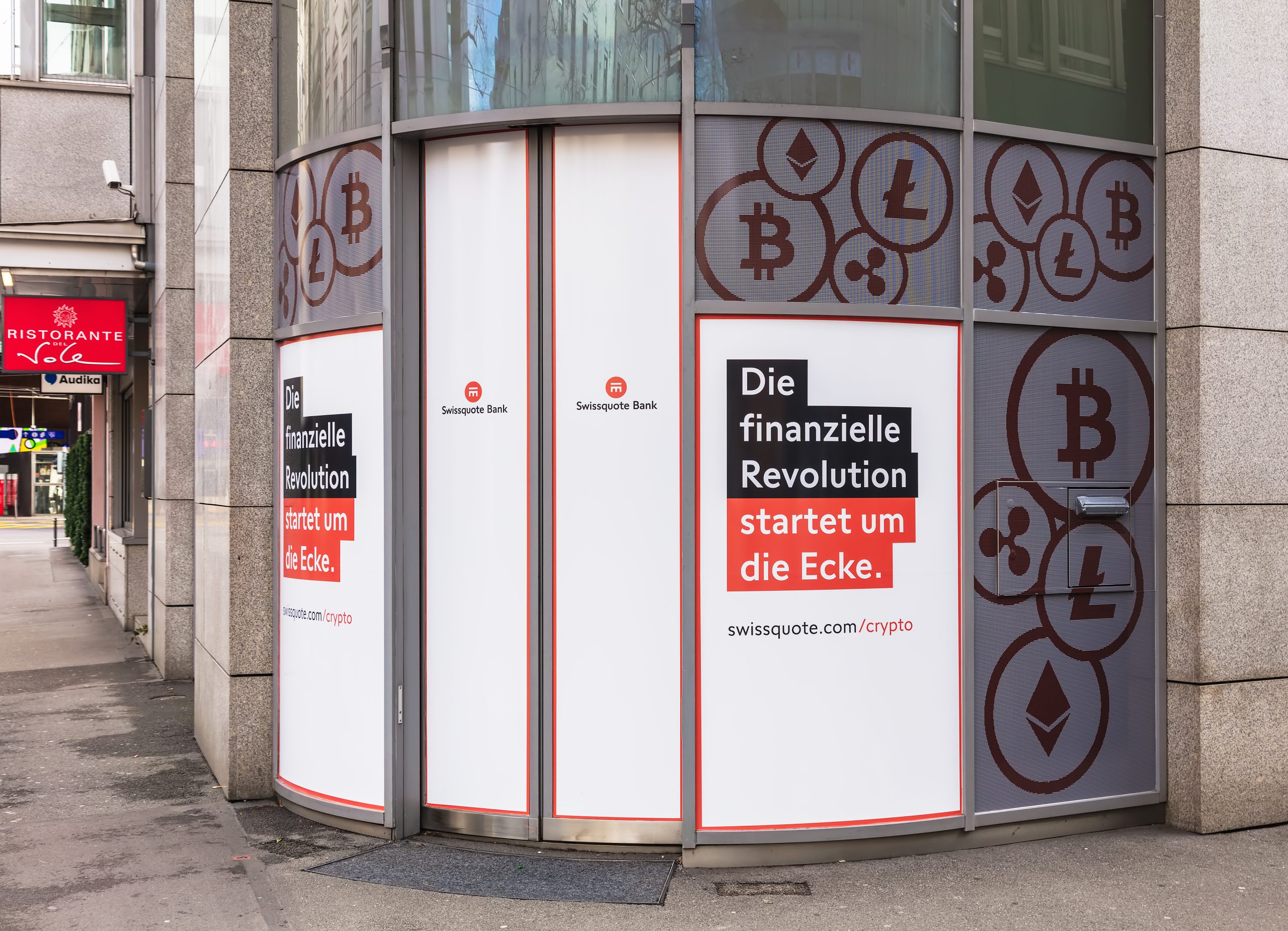 The exterior of a Swissquote Bank office, featuring large window advertisements for its cryptocurrency services.