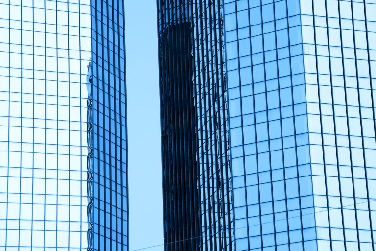 Two tall glass skyscrapers side by side in Zurich symbolizing the merger of Swiss insurers Baloise and Helvetia into a new financial powerhouse.