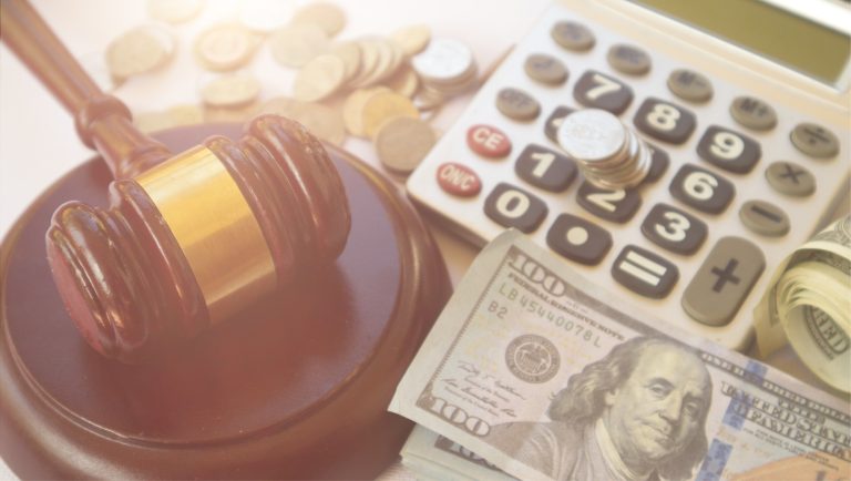 A judge's gavel rests next to a calculator, coins, and U.S. dollar bills. The image symbolizes the intersection of law and finance, representing the U.S. court case discussed in the 2025 article and its potential to redefine financial sanctions risk for banks.