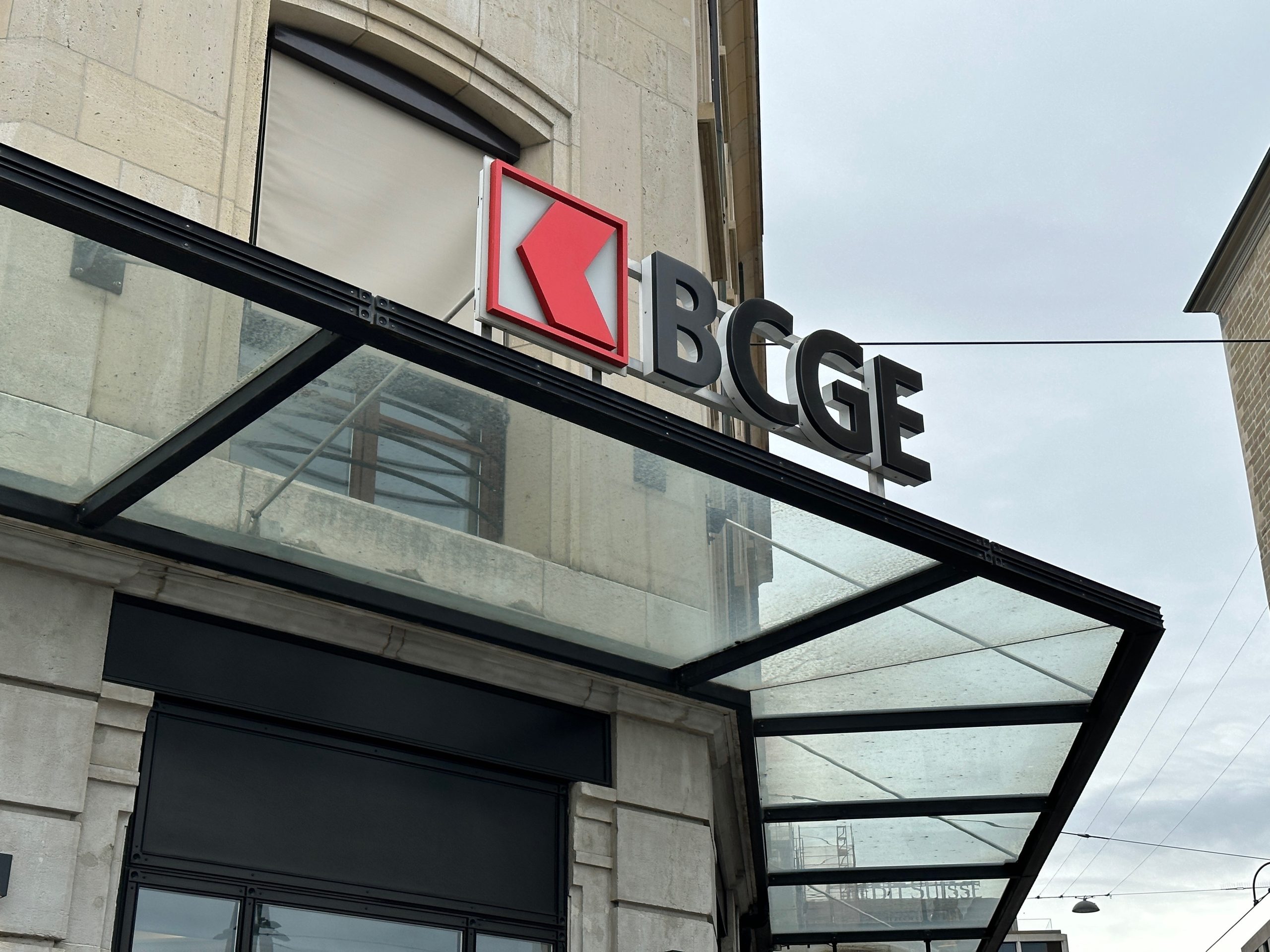 The exterior of a Geneva Cantonal Bank (BCGE) branch, showing the bank's logo and signage above the entrance. The image is used in a 2025 article to identify the institution at the center of a discussion about its recent stock split.