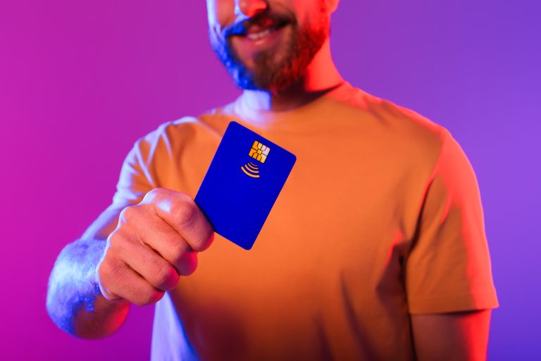 A person holds up a modern, blue digital bank card, representing the fintech bank Neon.