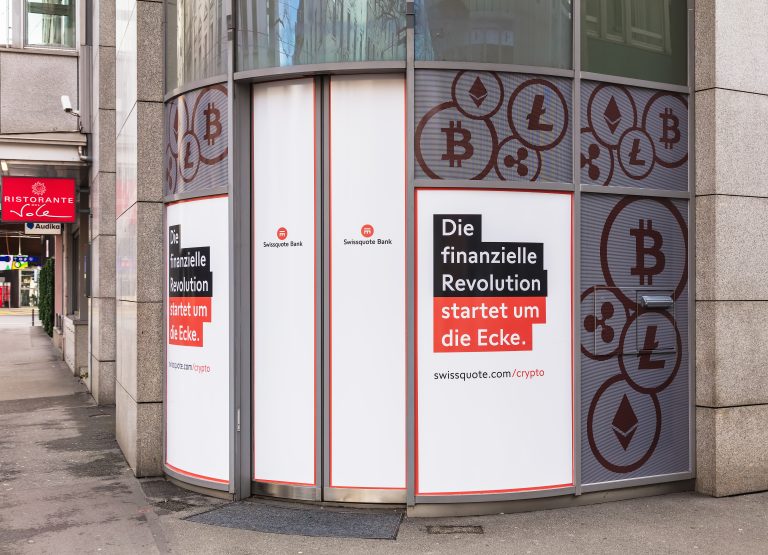 The exterior of a Swissquote Bank office, featuring large window advertisements for its cryptocurrency services.