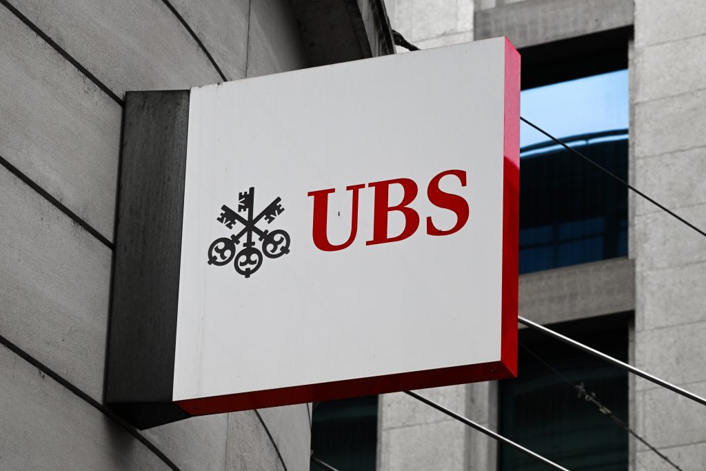 A projecting sign displaying the red UBS logo on a stone building facade.